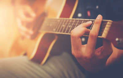 Midsection of man playing guitar