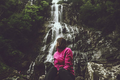 Woman looking at waterfall in forest