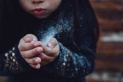 Close-up of girl blowing snow outdoors