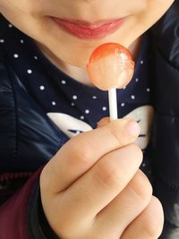 Midsection of girl holding lollipop at home