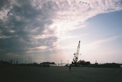 Silhouette cranes against sky at sunset