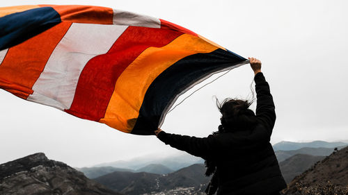 Woman with flag standing on mountain against clear sky