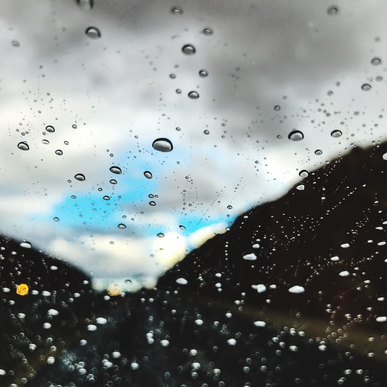 water, drop, window, indoors, wet, glass - material, rain, transparent, sky, droplet, cloud - sky, illuminated, water drop, glass, cloud, blue, mountain, cloudy, nature, full frame, no people, mountain range