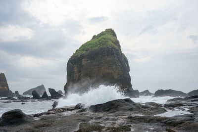 Sea waves splashing on beach against sky