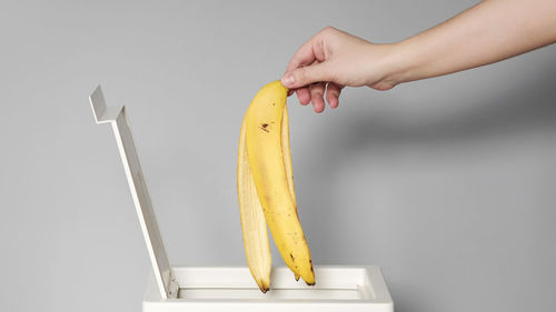 Close-up of hand holding strawberry over white background