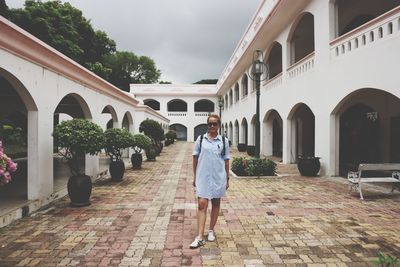 Rear view of woman walking on footpath amidst buildings