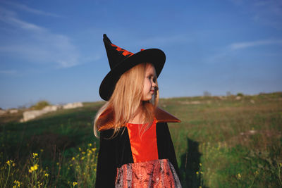 Woman wearing hat standing on field against sky