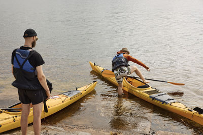 Man getting into kayak, while another man watching