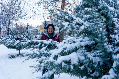 Portrait of smiling woman standing in snow covered park