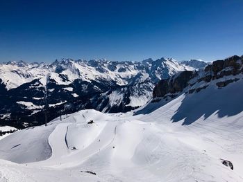 Scenic view of snowcapped mountains against clear blue sky