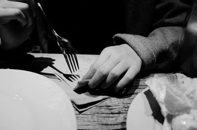 Midsection of person holding fork at table