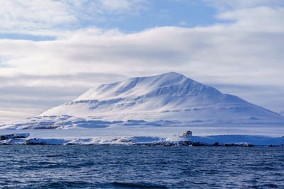 Scenic view of snowcapped mountains by sea against sky