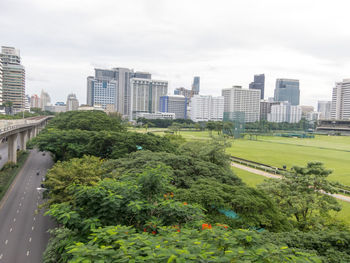 Trees and buildings in city against sky