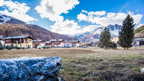 Houses on field by buildings against sky