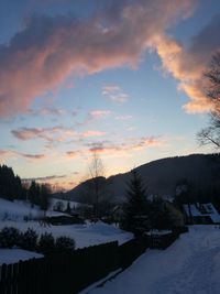 Snow covered landscape against sky during sunset