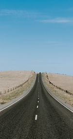 Road passing through land against sky