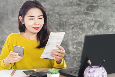 Young woman using mobile phone on table