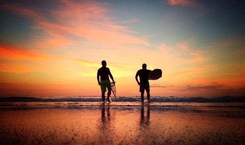 Silhouette of people on beach at sunset