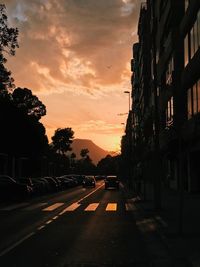 Road in city against sky at sunset