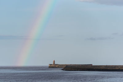 Scenic view of rainbow over sea against sky