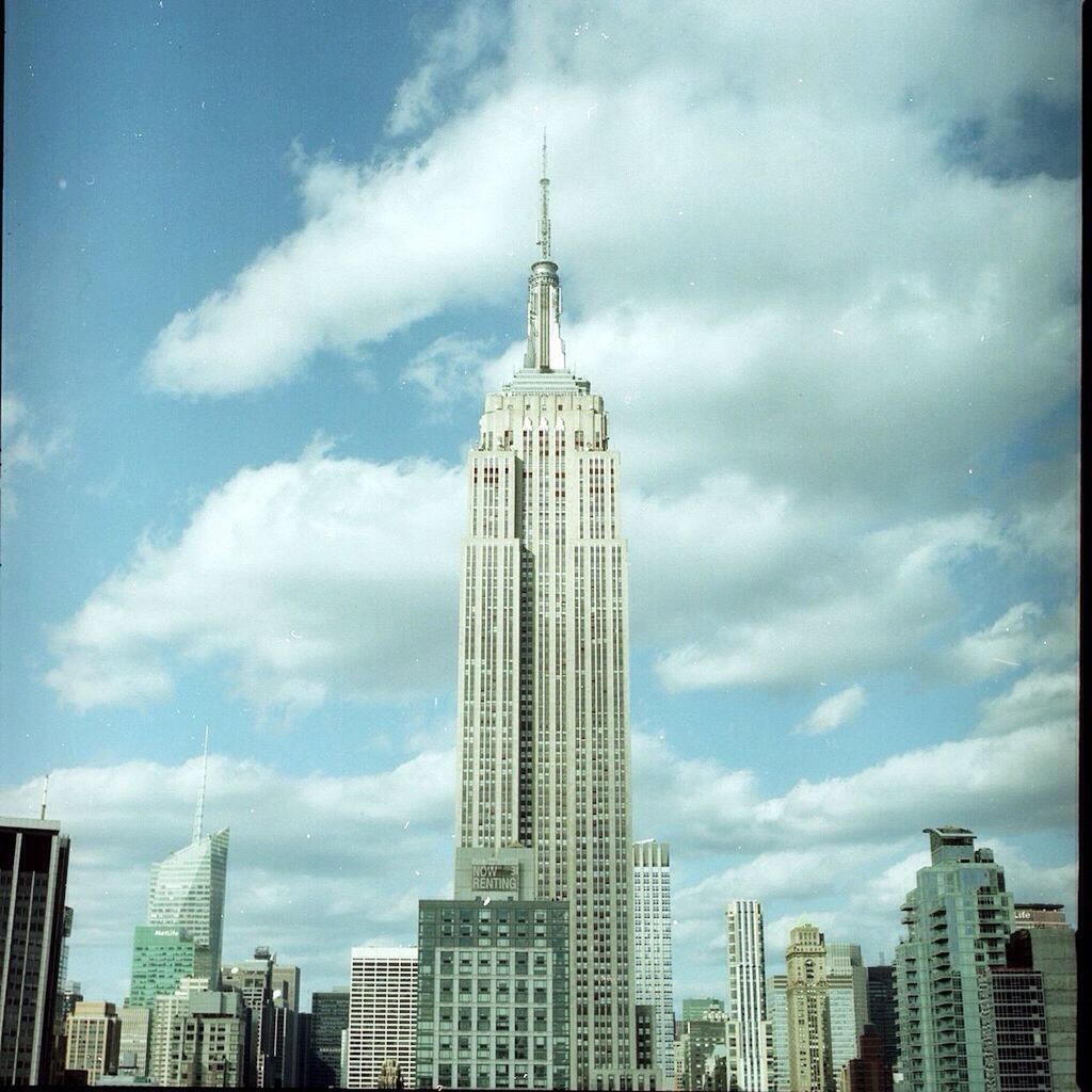 architecture, building exterior, built structure, city, skyscraper, tall - high, tower, modern, sky, capital cities, office building, famous place, travel destinations, international landmark, cloud - sky, tourism, travel, low angle view, empire state building, financial district