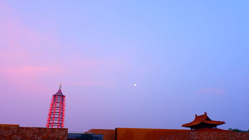 Low angle view of illuminated building against sky at sunset