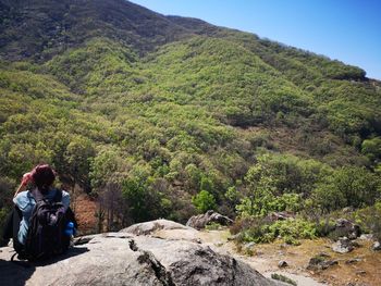 Rear view of people sitting on rock against mountain