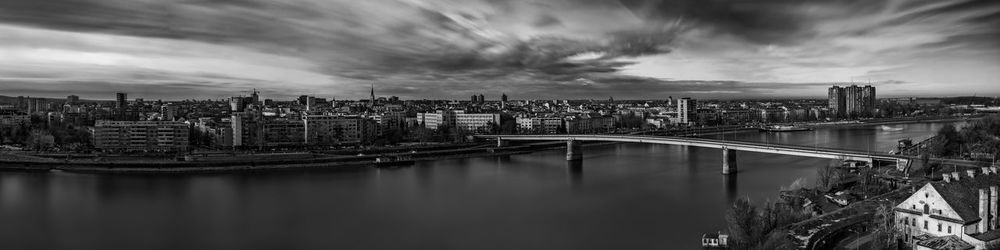 Bridge over river by buildings against sky in city