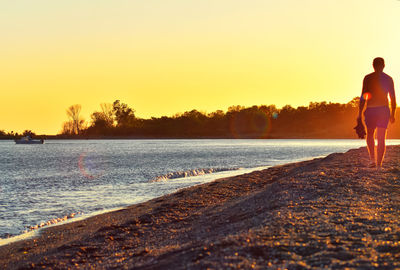 Full length of man on beach against sky during sunset