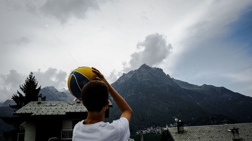 Rear view of woman standing on mountain against sky