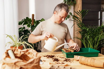 Side view of man using mobile phone while sitting on table