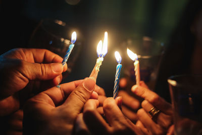 Close-up of hands holding burning candles