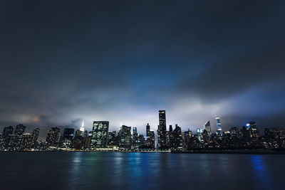 Illuminated modern buildings in city against sky at night