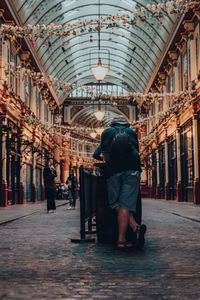 Rear view of man and woman walking in illuminated building