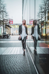 Full length of woman walking by glass