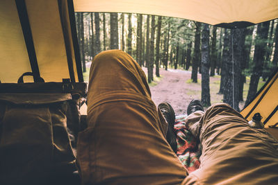 Low section of person relaxing in tent at forest