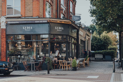 Chairs and tables in street amidst buildings in city