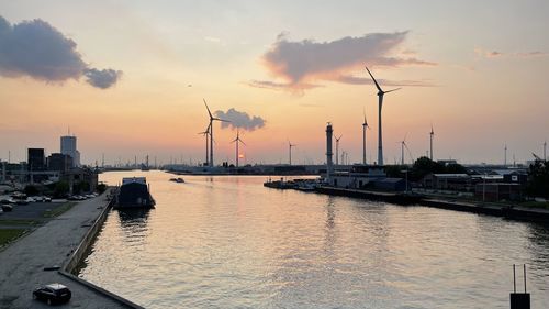 Boats in river against sky during sunset