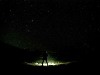 Silhouette person standing on field against sky at night