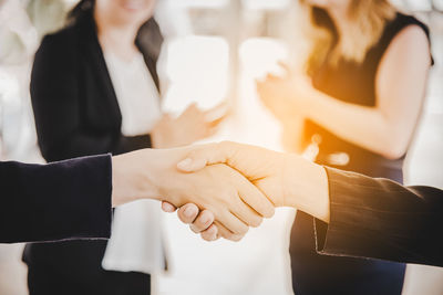 Close-up of businesswomen shaking hands with colleagues