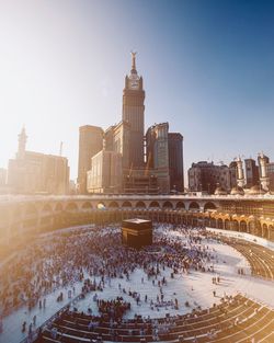 High angle view of people in mecca by modern buildings against clear sky