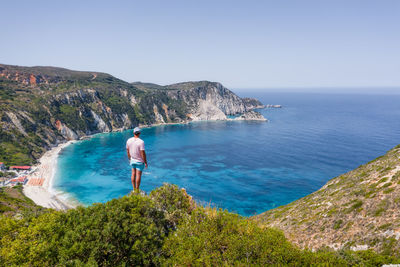 Rear view of man standing by sea against sky