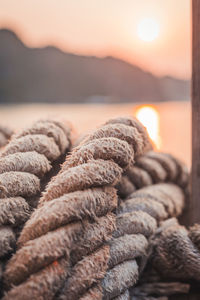 Close-up of rope on beach against sky during sunset