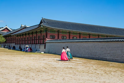 Rear view of people walking outside temple against clear sky