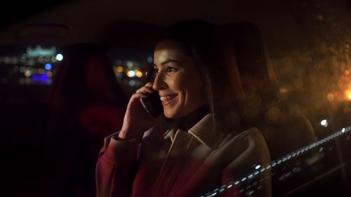 Woman commuting from office in luxury car at night. calling