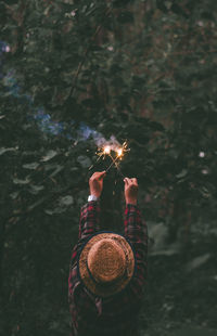 Rear view of woman holding sparklers in forest