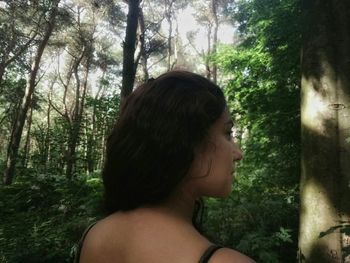 Woman standing on tree trunk in forest