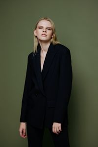 Portrait of businesswoman standing against wall