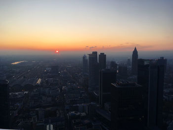 Aerial view of buildings in city against sky during sunset