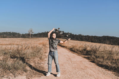 Rear view of man photographing while standing on field against clear sky